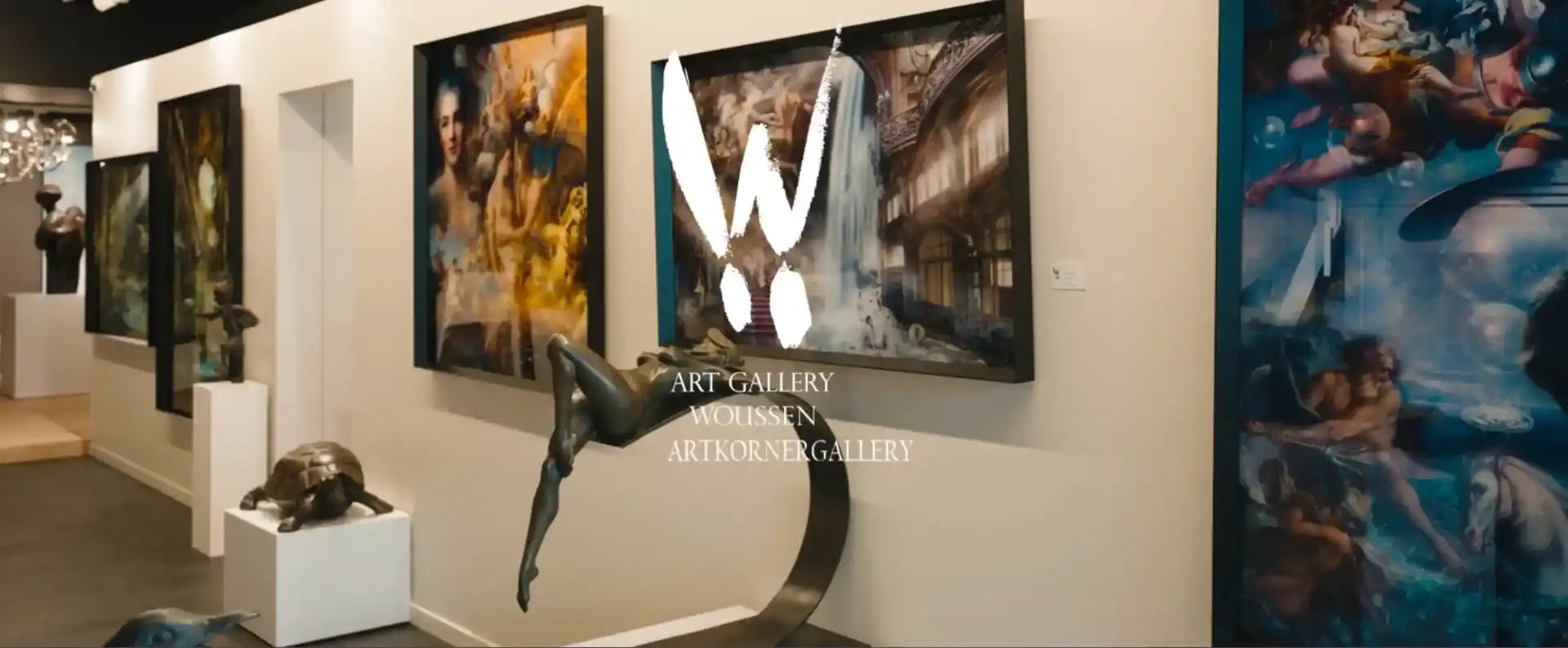 Intérieur d'une galerie d'art présentant des peintures, photos et des sculptures modernes, incluant une statue de femme en mouvement et un grand tableau orné d'un W blanc et artkornergalley