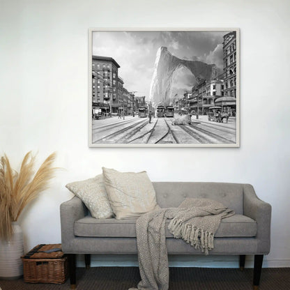 Tableau noir et blanc montrant des tramways devant un iceberg géant, accroché au-dessus d'un canapé gris avec coussins.